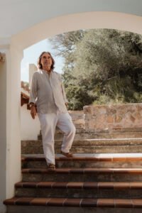 Der Reisedesigner steht in einer mallorcinischen Finca auf einer Treppe.