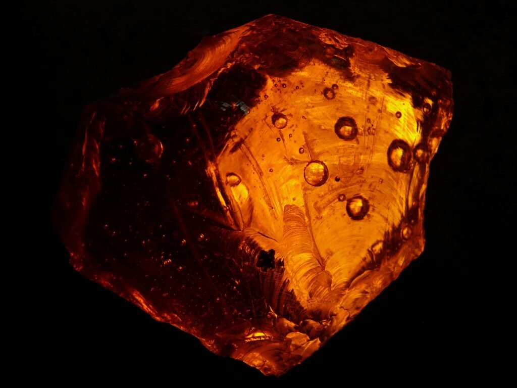 A beautifully illuminated orange amber stone with detailed textures and patterns.