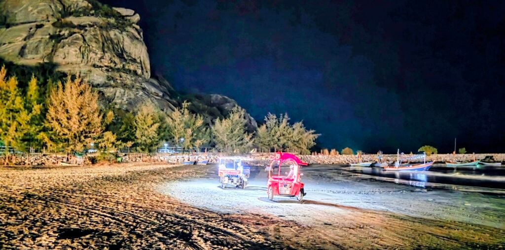 Verkaufs Tuk-Tuks am Strand mit Fischerbooten